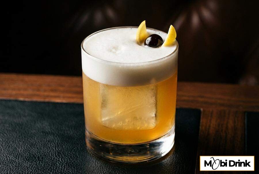 Koktajl Amaretto Sour z białą pianką i wiśnią
